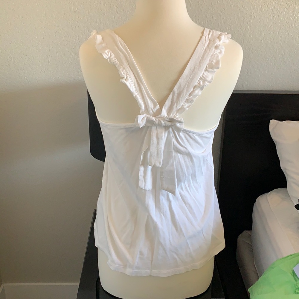 White tank with ruffle shoulders and bow back.